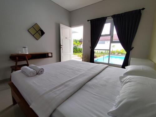 a bedroom with a large white bed with towels on it at Menepi Bali in Uluwatu