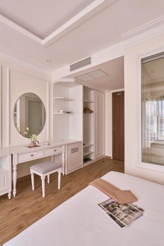 a white bedroom with a desk and a mirror at Nature Hotel and Suite in Da Lat