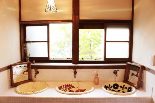 2 wastafels in een badkamer met 2 ramen bij Roku Hostel Hiroshima in Hiroshima