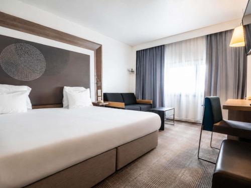 a hotel room with a large bed and a desk at Novotel Nantes Centre Gare in Nantes