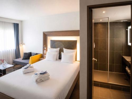 a hotel room with a bed with towels on it at Novotel Nantes Centre Gare in Nantes