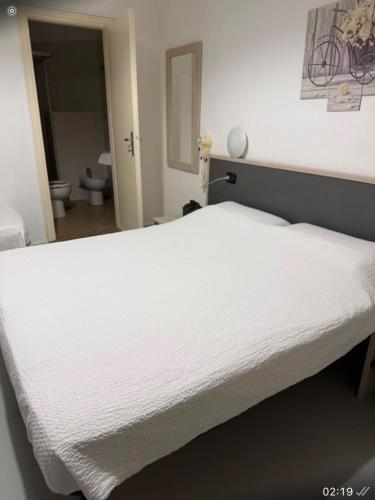 a white bed in a room with a bathroom at La voglia albergo in Villanova sullʼArda