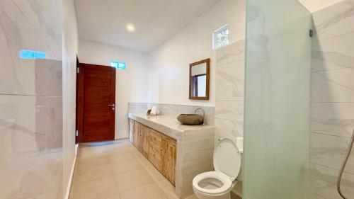 a bathroom with a toilet and a sink and a mirror at ANANDA Bingin Guesthouse in Bingin Beach