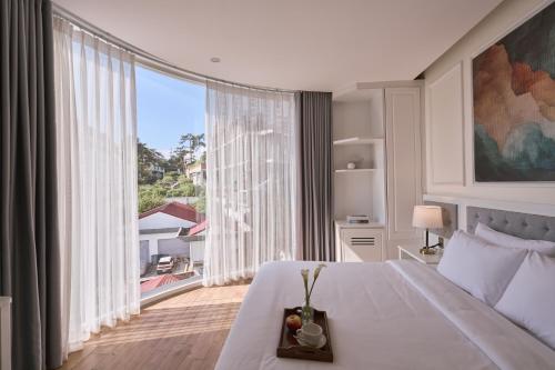 a bedroom with a large bed and a large window at Nature Hotel and Suite in Da Lat