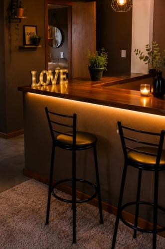 two chairs sitting at a bar with a love sign at Aconchego Valença & Spa in Nova Friburgo