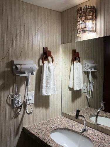 a bathroom with a sink and a mirror and towels at G2 Beach Hotel in Aquiraz