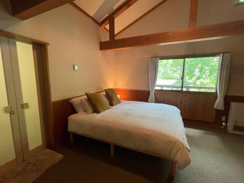 a bedroom with a bed and a large window at Ikiru Lodge in Yamanouchi