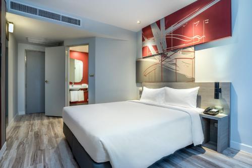a bedroom with a white bed and a painting on the wall at ibis Bangkok IMPACT in Nonthaburi