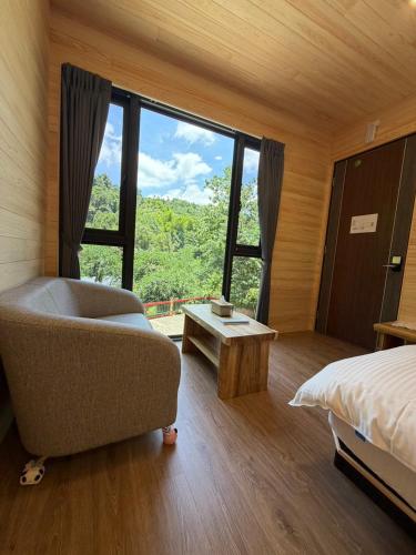 a bedroom with a bed and a couch and a large window at 木木杉民宿 in Puli