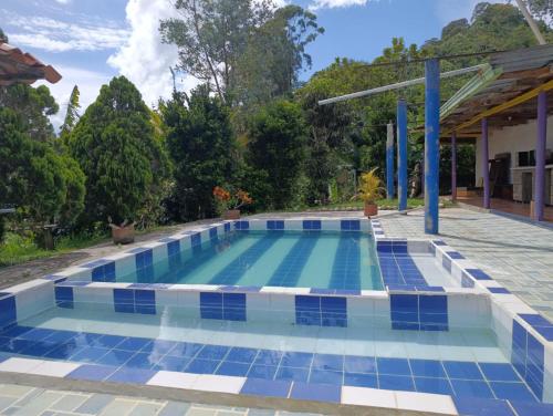 a swimming pool with blue and white tiles on the ground at Finca de las banderas in Jardin