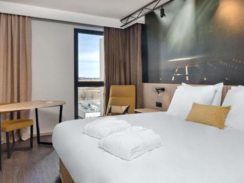 a hotel room with a large white bed and a desk at Mercure Montpellier Centre Comédie in Montpellier