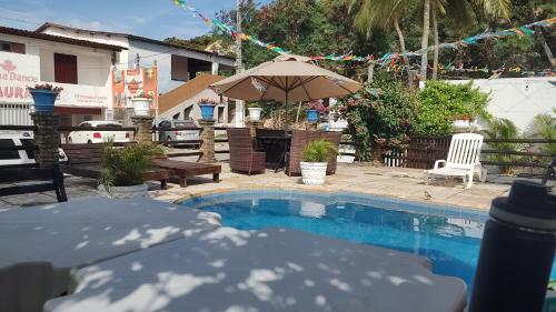 a pool with an umbrella and a table and chairs at Pousada Rosa dos Ventos in Genipabu