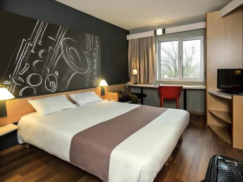 ein Hotelzimmer mit einem großen Bett und einem Schreibtisch in der Unterkunft ibis Dinant Centre in Dinant