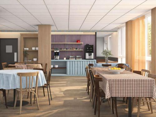 a dining room with tables and chairs and a kitchen at Greet Lourdes Centre Pyrenees in Lourdes