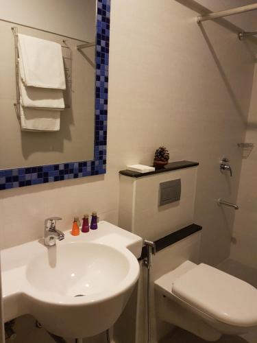 a bathroom with a white sink and a toilet at Utse Suites in Bengaluru