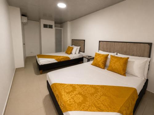 a hotel room with two beds with yellow pillows at HOTEL ELITE in Cali
