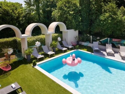 an overhead view of a swimming pool with chairs and a pink inflatablelatable elephant at Ibis Styles Cognac in Châteaubernard