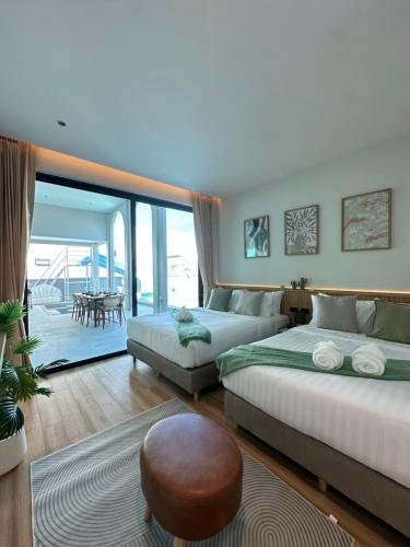 a bedroom with two beds and a living room with a table at April Pool Day Villa Cha-am in Cha Am