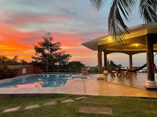 a swimming pool with a gazebo and a sunset at Hotel Miraflores in El Cuco