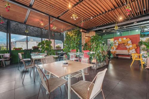 a restaurant with tables and chairs and plants at Hotel Medellin Arte in Medellín