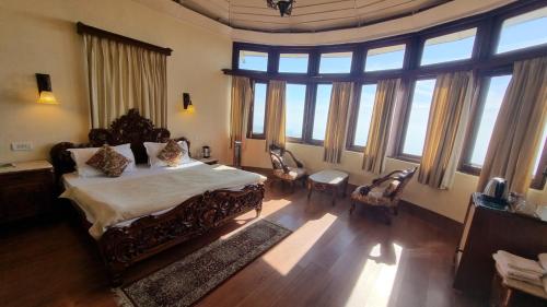 a bedroom with a large bed and windows at Hotel Padmini NIvas in Mussoorie