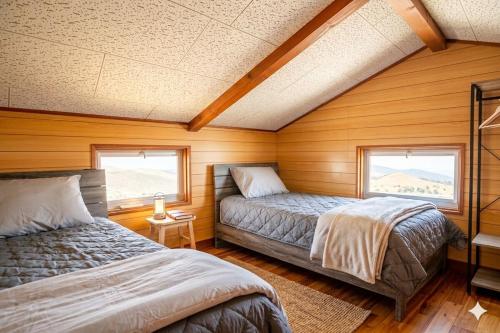 zwei Betten in einem Zimmer mit Holzwänden und Fenstern in der Unterkunft Rumble Base 山口県光市虹ヶ丘 in Hikari