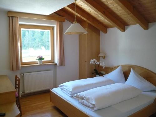 a bedroom with a bed with white sheets and a window at Residence Aster in Solda