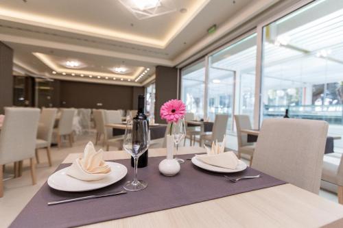 a table with a bottle of wine and a pink flower on it at Hotel Crikvenica in Crikvenica