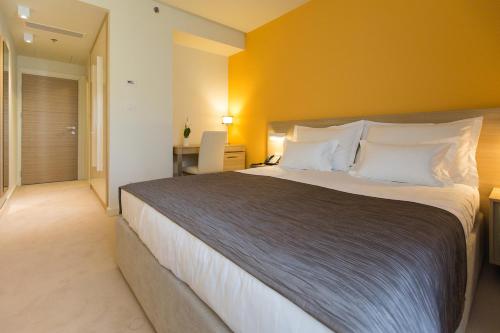 a bedroom with a large bed with a yellow wall at Hotel Crikvenica in Crikvenica