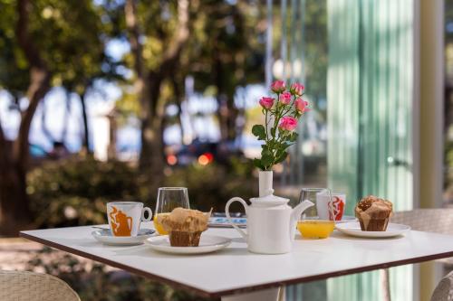 a table with plates of food and a vase with flowers at Hotel Crikvenica in Crikvenica