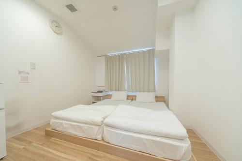 a white bedroom with a large white bed in it at コインズホステル天神ペット宿泊可 in Fukuoka