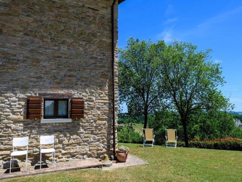 a group of chairs sitting next to a brick building at Flat on a farm with swimming pool and many activities in SantʼAngelo in Vado