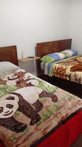 two beds with a panda bear pattern on them at Hotel Los alpes in Garagoa
