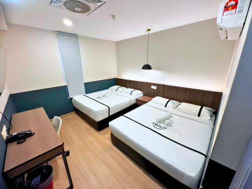 a small room with two beds and a desk at Smile Hotel Subang USJ in Subang Jaya