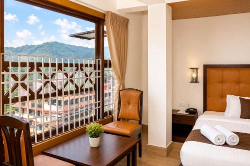 a bedroom with a balcony with a bed and a desk at Gangtok Central Rooms in Gangtok