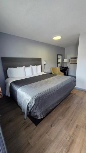 a bedroom with a large bed and a wooden floor at Plaza Motel in Joplin