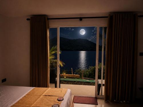 a bedroom with a view of the water and moon at Elee Villa - Waterfront Retreat with Victoria Reservoir & Mountain Views in Teldeniya