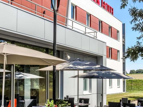 two tables with umbrellas in front of a hotel at Ibis Saint-Genis-Pouilly Genève in Saint-Genis-Pouilly