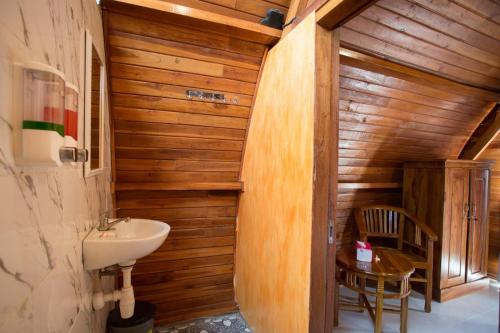 a bathroom with a sink and a wooden wall at Garuda Dive & Accomodation Nusa Penida in Nusa Penida