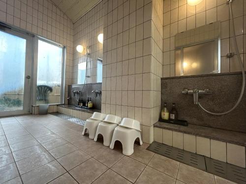 a bathroom with a row of white chairs and a shower at Lasting Hotel in Kushiro