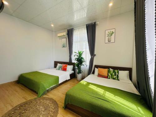 two beds in a room with green sheets at Arden Villa Quy Nhơn in Quy Nhon