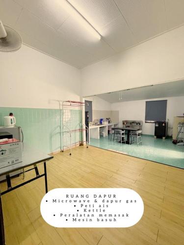 a large empty room with a table and a kitchen at Harumi Guesthouse in Marang