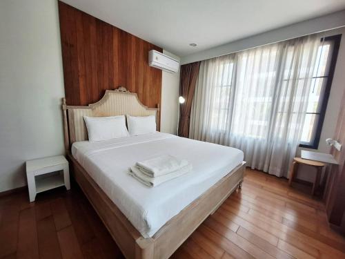 a bedroom with a large white bed with wooden floors and windows at บ้านแสนสุขคอนโดติดทะเล By Nichahome in Hua Hin