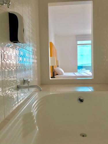 a white bath tub in a bathroom with a mirror at Mejor Hotel, Centro Medellín, Opera, adults only entertainment in Medellín