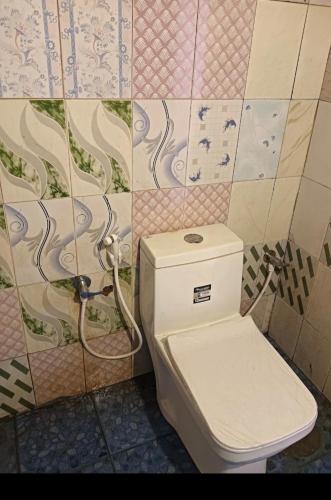 a bathroom with a toilet and a tile wall at Paradise beach homestay in Alleppey