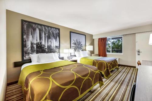 a hotel room with two beds and a window at Super 8 by Wyndham Riviera Beach West Palm Beach in Riviera Beach