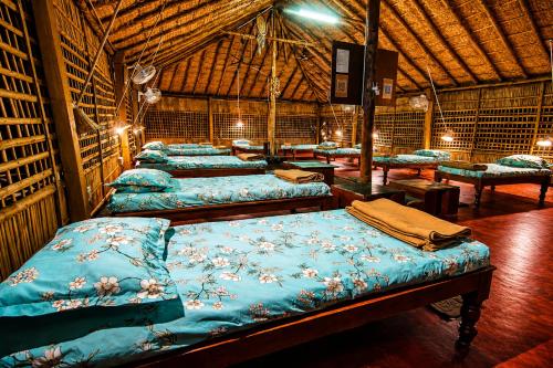 a group of beds in a room with a roof at Gowri Guest House in Hampi