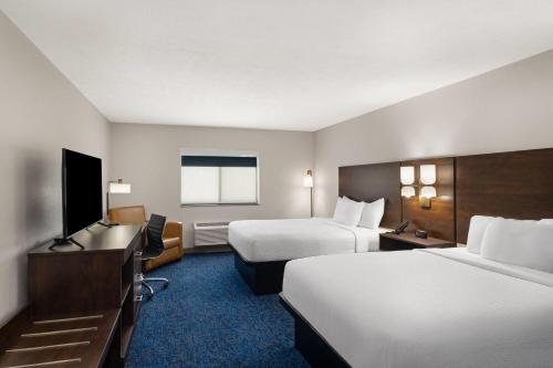 a hotel room with two beds and a flat screen tv at Baymont by Wyndham Oacoma in Oacoma