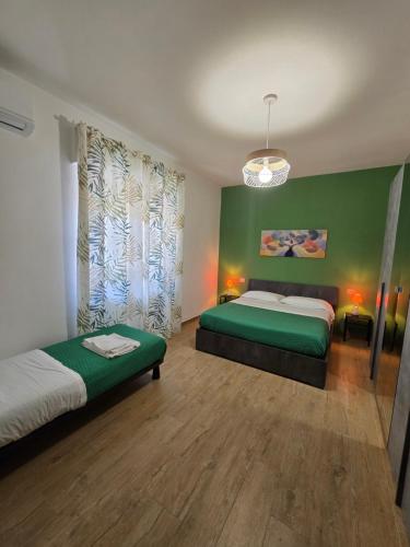 a bedroom with two beds and a green wall at Filoverde vicino il CONI e il mare in Formia