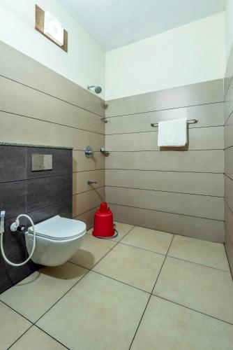 a bathroom with a toilet and a red bucket at Hotel Beverly Residency - Near Nileshwar Railway Station in Nīleshwar